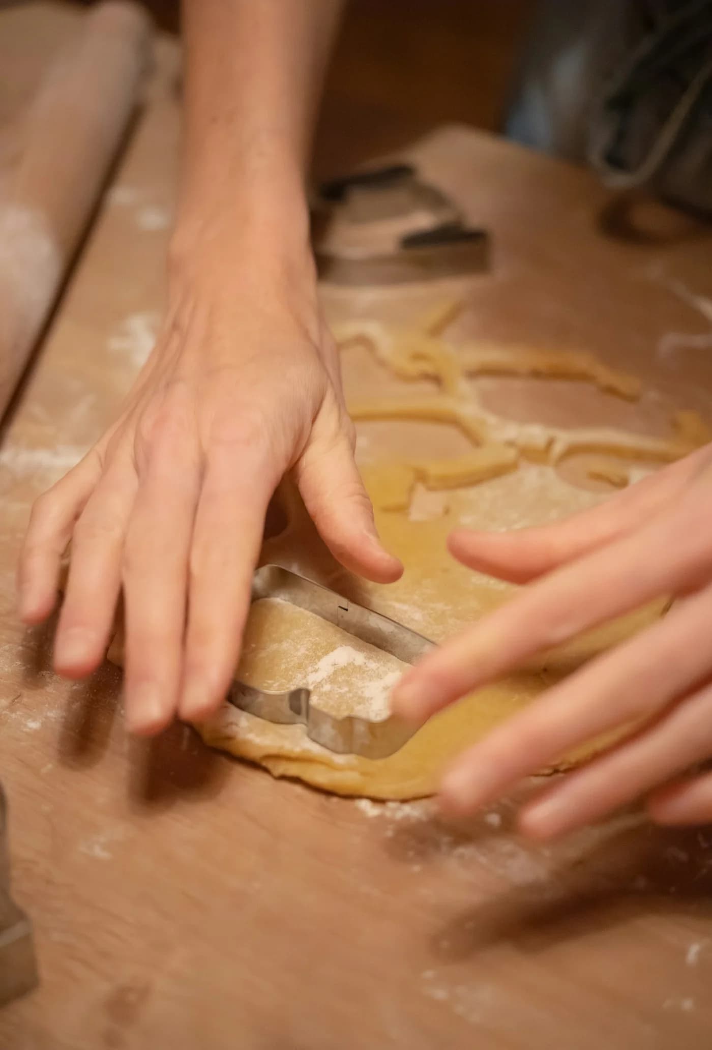 Hands cutting cookie dough with cutters